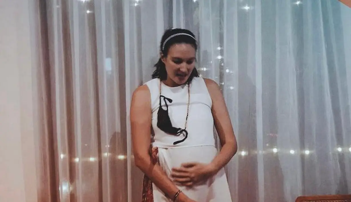 Sambil mengelus perut besarnya, Nadine Chandrawinata terlihat cantik pakai dress putih dan rok batik. (Instagram/nadinelist).