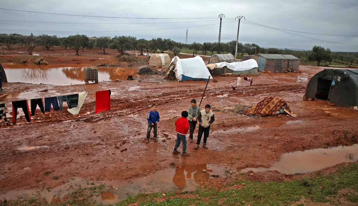 Anak-anak berkumpul saat banjir menggenangi lokasi pengungsian di Kamp Cordoba, Batabu, Idlib, Suriah, Rabu (16/1). Banjir menggenangi tenda-tenda pengungsian mereka. (Aaref Watad/AFP)