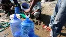 Warga memanfaatkan air bersih dari kebocoran pipa PDAM di Jalan Lagarutu, Palu Sulawesi Tengah, Rabu (3/10). Mereka mengisi air dari pipa PDAM menggunakan selang yang disalurkan ke dalam galon. (Liputan6.com/Fery Pradolo)