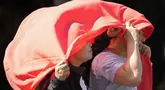Seorang pria dan perempuan menutupi kepala mereka dengan kain untuk melindungi mereka dari sinar matahari di Manila, Filipina, Senin (29/4/2024). (AP Photo/Aaron Favila)