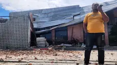 Seorang pria berbicara di telepon selulernya di dekat sebuah bangunan yang rusak akibat gempa di Palu, Sulawesi Tengah, Selasa 16 Juni 2026. (AP Photo/Josua Marunduh)