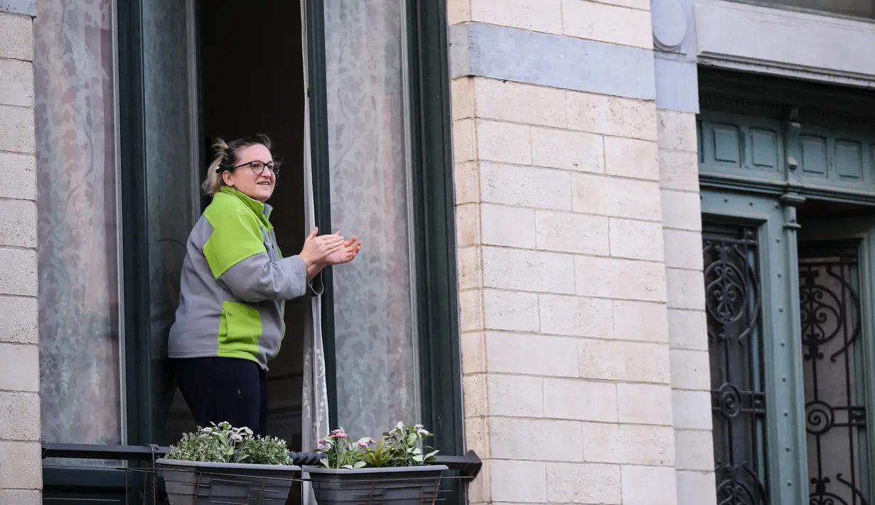Seorang wanita bertepuk tangan dari jendela untuk menunjukkan penghormatan terhadap orang-orang yang bertugas di garis depan melawan pandemi virus corona COVID-19 di Brussel, Belgia,Selasa (14/4/2020). Kasus COVID-19 di Belgia sebanyak 31.119 positif dan 4.157 meninggal. (Xinhua/Zhang Cheng)