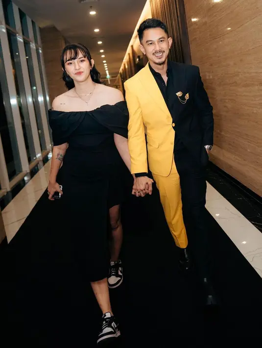 Di sampingnya, ada sang istri Dahlia Poland yang terlihat elegan dengan off shoulder hitamnya. Sentuhan sporty pun diberikan lewat sneakers monokrom yang dia kenakan.  [@snap.nuel]