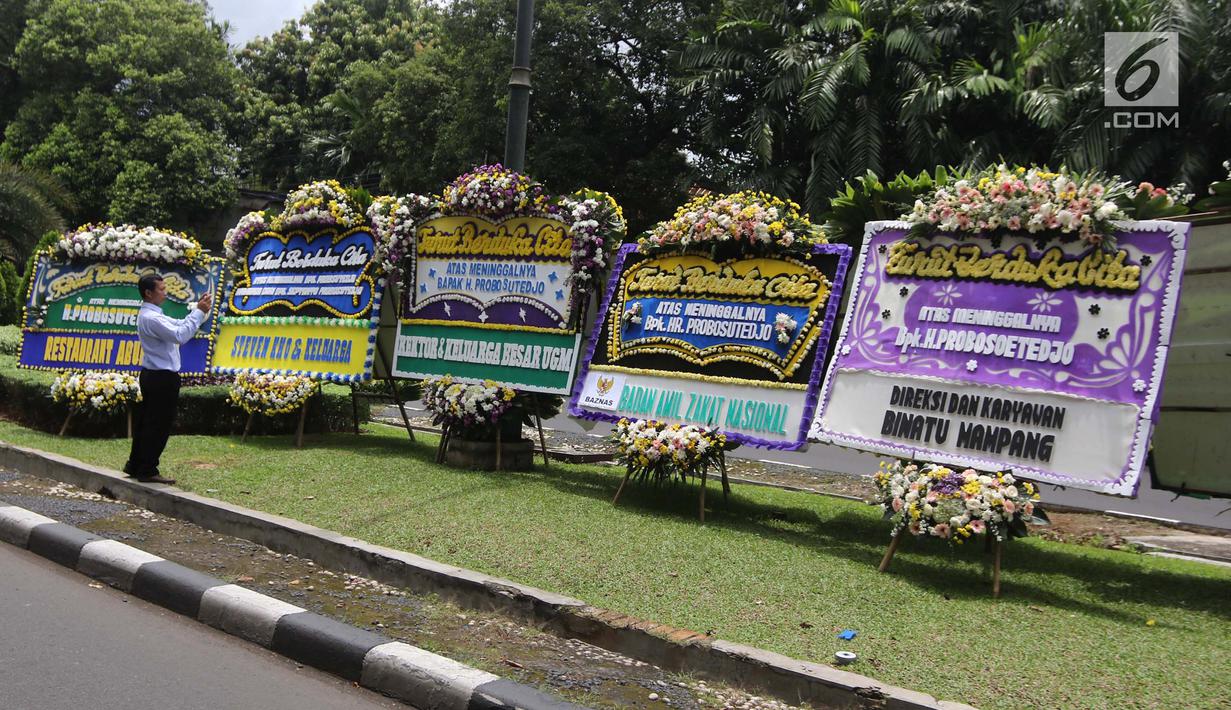 Warga mengambil gambar karangan bunga ucapan duka cita untuk Probosutedjo yang memenuhi Jalan Diponegoro, Jakarta, Senin (26/3). Probosutedjo meninggal dunia di RSCM Kencana Jakarta Pusat. (Liputan6.com/Arya Manggala)