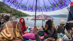 Anggota keluarga penumpang menunggu proses pencarian yang dilakukan tim SAR terhadap korban tenggelamnya KM Sinar Bangun di pelabuhan feri Danau Toba, Sumatera Utara, Rabu (20/6). Kapal tersebut membawa ratusan penumpang. (AFP PHOTO/IVAN DAMANIK)