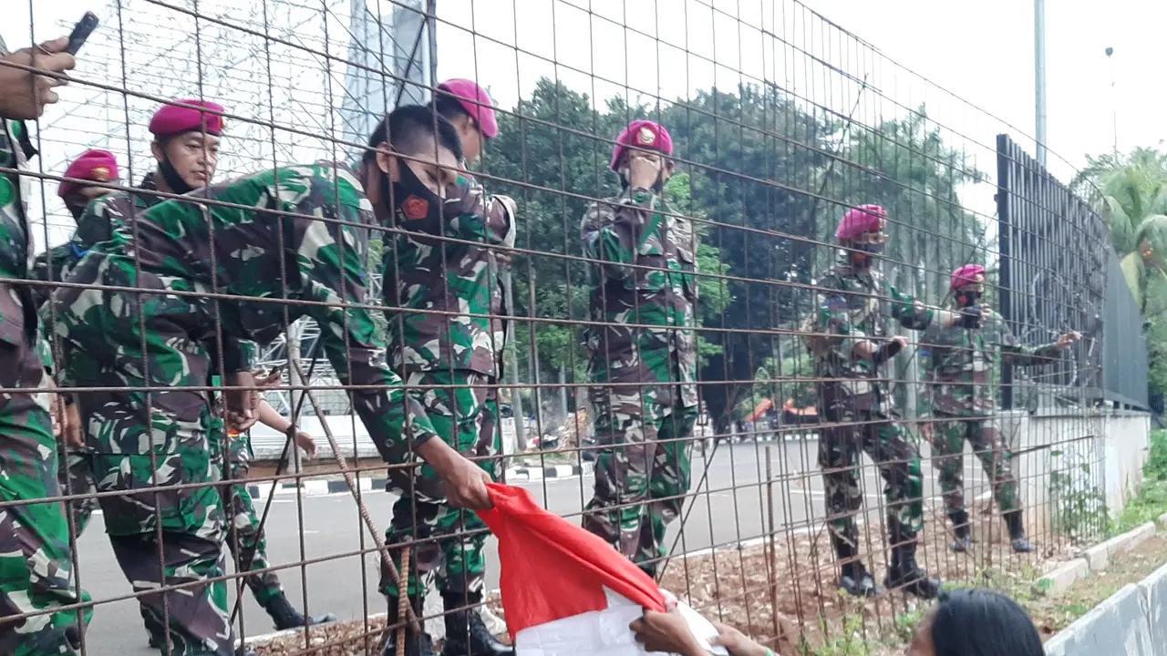 Buruh wanita Eva menyerahkan bendera merah putih ke anggota TNI di sela demo. (Ady Anugrahadi/Liputan6.com).