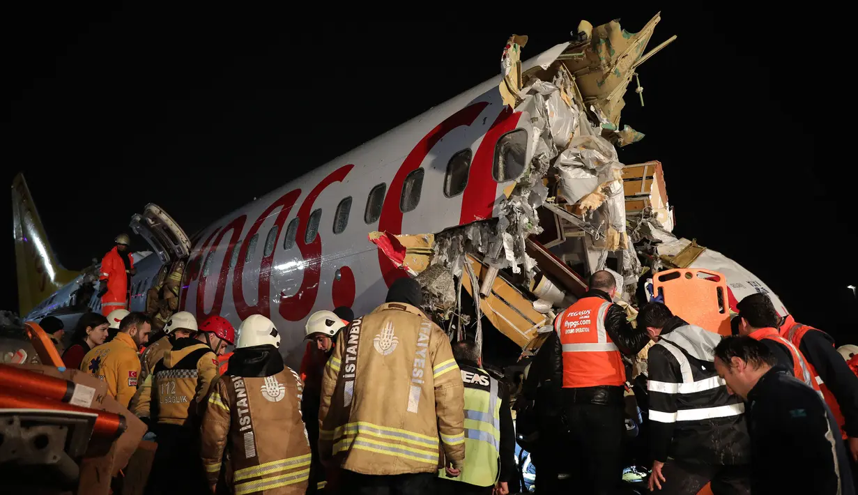 Tim penyelamat dan petugas pemadam kebakaran bekerja setelah sebuah pesawat tergelincir di landasan pacu Bandara Sabiha Gokcen, Istanbul, Turki, Rabu (5/2/2020).  Kecelakaan ini mengakibatkan bandara berhenti beroperasi. (Can Erok/DHA via AP)
