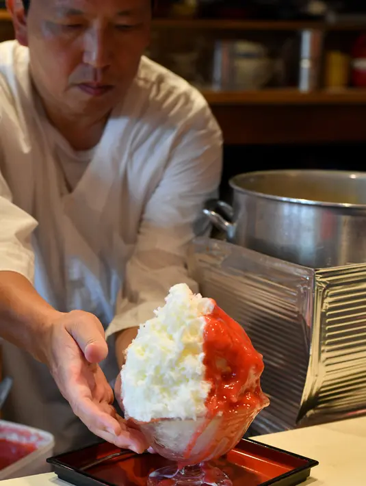 Pemilik toko Koji Morinishi menyajikan kakigori atau es serut di distrik Yanaka Tokyo, Jepang (21/6/2019). Kakigori atau es serut ini menggunakan es alami yang dibuat langsung dari pegunungan di utara Tokyo, Yuichiro Yamamoto. (AFP Photo/Toshifumi Kitamura)
