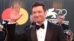 Hugh Jackman berpose untuk fotografer setibanya di pemutaran perdana film 'The Son' selama Festival Film Venesia edisi ke-79 di Venesia, Italia, Rabu (8/9/2022). Aktor tampan tersebut terlihat tersenyum sambil mengangkat tangannya, menyapa media dan penonton yang hadir. (Joel C Ryan/Invision/AP)