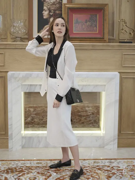 Satu lagi inspirasi tampilan hitam putih dari Cathy Sharon untuk ke kantor dengan cardigan dan rok midi. Plus aksesori tas slempang dan sepatu loafer (Foto: Instagram @cathysharon)
