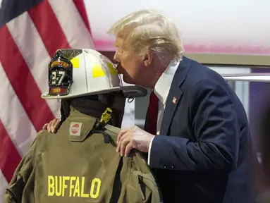 Kandidat presiden dari Partai Republik, mantan Presiden Donald Trump, mencium helm Corey Comperatore saat Konvensi Nasional Partai Republik di Fiserv Forum di Milwaukee, Wisconsin, Kamis (17/7/2024). (AP Photo/Charles Rex Arbogast)