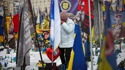 Perang antara Rusia dan Ukraina berdampak pada krisis kemanusiaan dan ekonomi yang sangat besar. Tampak dalam foto, seorang warga setempat bereaksi saat mengunjungi tugu peringatan sementara untuk tentara Ukraina dan asing di Lapangan Kemerdekaan, Kyiv, saat peringatan keempat invasi Rusia ke Ukraina, Selasa 24 Februari 2026. (HENRY NICHOLLS/AFP)