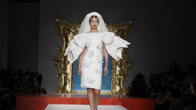 Model Gigi Hadid berjalan di catwalk memakai koleksi Moschino Spring-Summer 2020 selama pekan mode di Milan, Italia (19/9/2019). Gigi tampil anggun dengan sentuhan apik pada balutan gaun pengantin berwarna putih untuk showcase unik yang terinspirasi oleh Alice In Wonderland. (AP Photo/Luca Bruno)