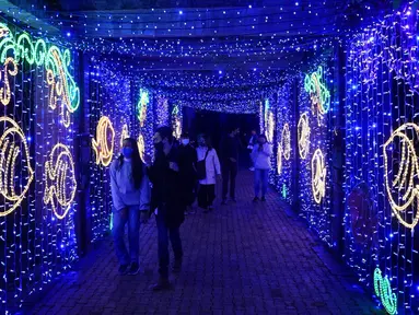 Pengunjung berjalan melewati lampu Natal yang menghiasi Kebun Raya Jose Celestino Mutis di Bogota, Kolombia, 16 Desember 2021. Dari populasi Kolombia yang berjumlah 49.650.000 jiwa, sekitar 71 persen di antaranya beragama Katolik. (AP Photo/Fernando Vergara)