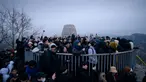 Orang-orang berkumpul di sudut pandang yang menghadap ke cakrawala kota untuk menyaksikan matahari terbit pertama tahun baru, meskipun dalam kondisi mendung, di Seoul, Korea Selatan (1/1/2020). (AFP/Ed Jones)