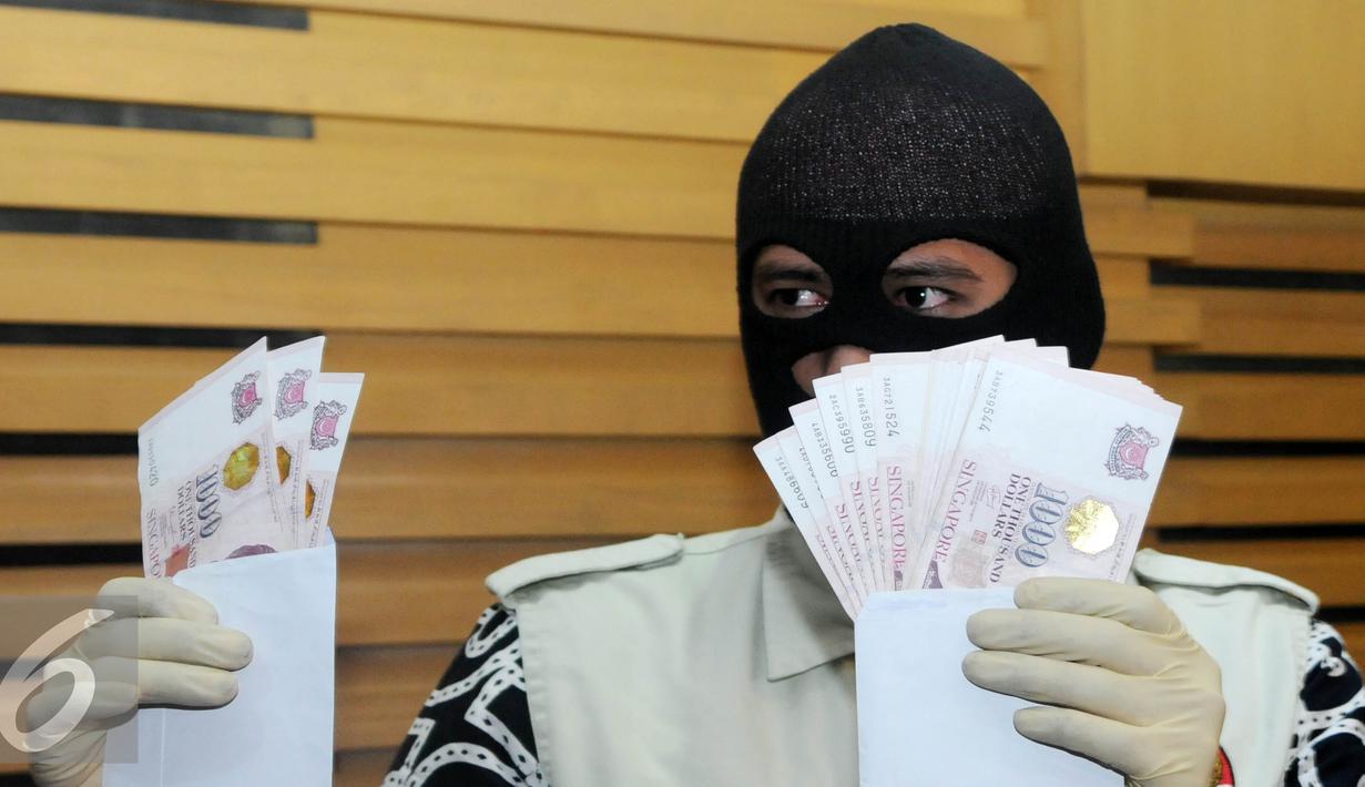 Petugas memperlihatkan barang bukti dalam OTT yang dilakukan KPK terhadap Panitera Pengganti Pengadilan Negeri Jakarta Pusat dengan mengamankan barang bukti uang sebesar 28.000 dolar Singapura, Jakarta, Jumat (1/7). (Liputan6.com/Helmi Afandi)