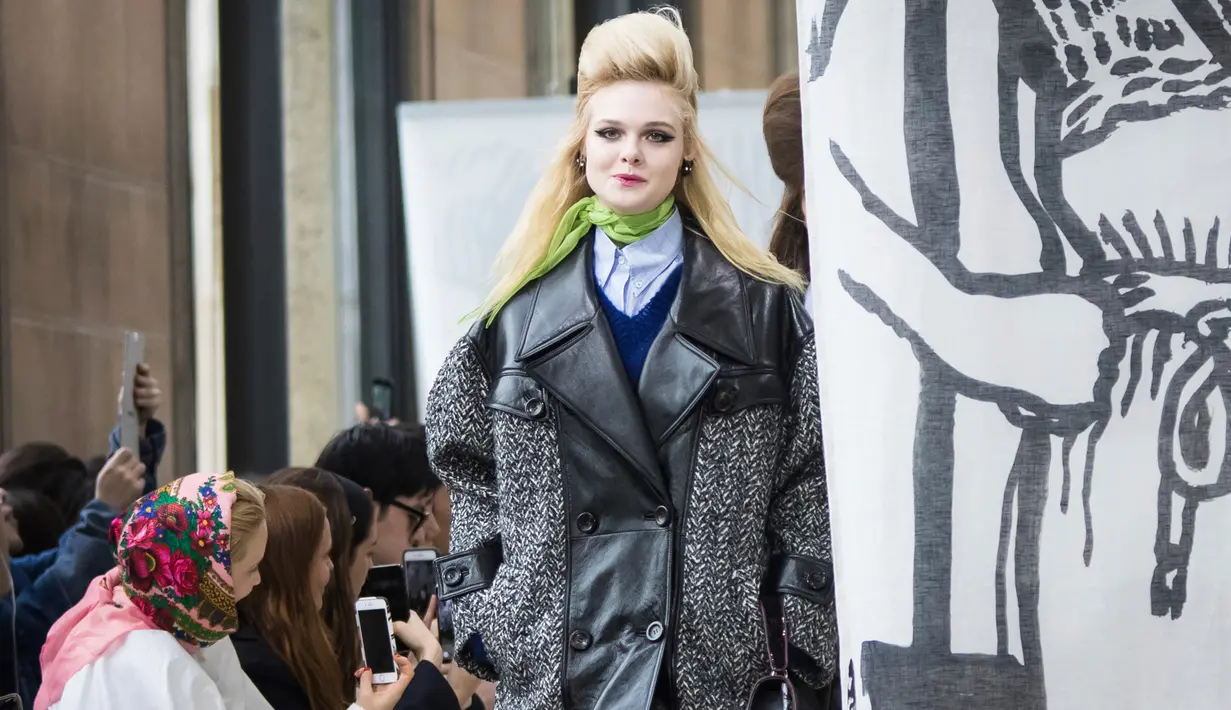 Aktris Elle Fanning memperagakan busana karya Miu Miu pada pagelaran Paris Fashion Week Fall-Winter 2018, Selasa (6/3). Adik dari Dakota Fanning ini memakai coat abu-abu berbahan kulit dengan cutting besar. (Vianney Le Caer/Invision/AP)