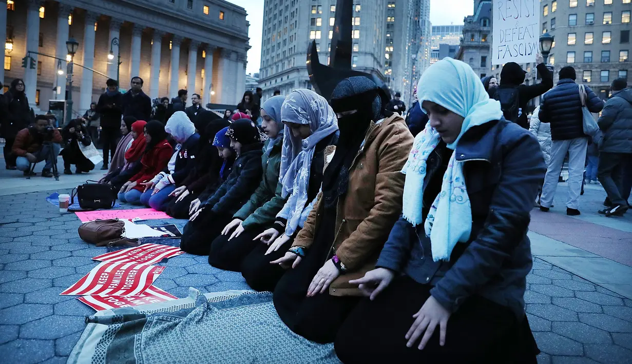 Sejumlah wanita muslim terlihat khusuk saat menggelar salat berjemaah sebelum melakukan aksi protes di Manhattan, New York (1/2). Mereka mengecam kebijakan Donald Trump terkait larangan imigran dari negara mayoritas muslim masuk ke AS. (AFP/Spencer Platt)