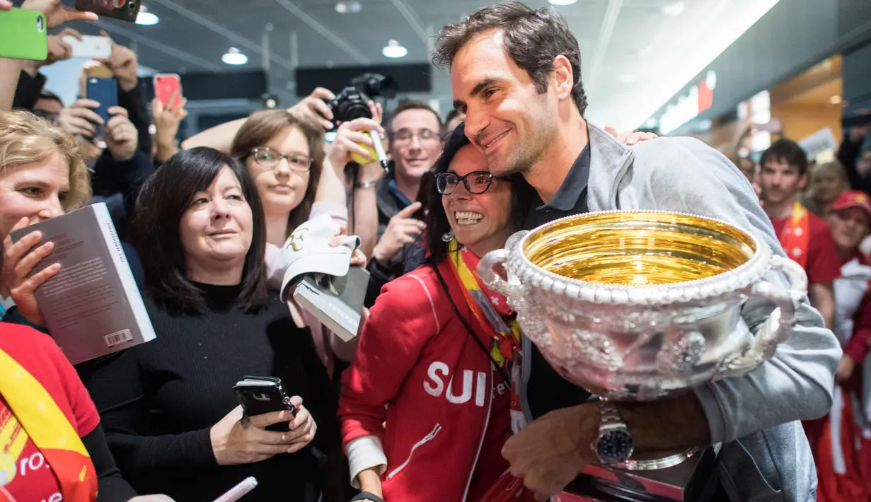 Penggemar wanita berpose dengan Roger Federer yang membawa trofi Australia Terbuka 2018 di Bandara Zurich, di Kloten, Swiss, (30/1). Federer mengalahkan petenis Kroasia Marin Cilic 6-2, 6-7(5), 6-3, 3-6, 6-1. (Ennio Leanza/Keystone via AP)