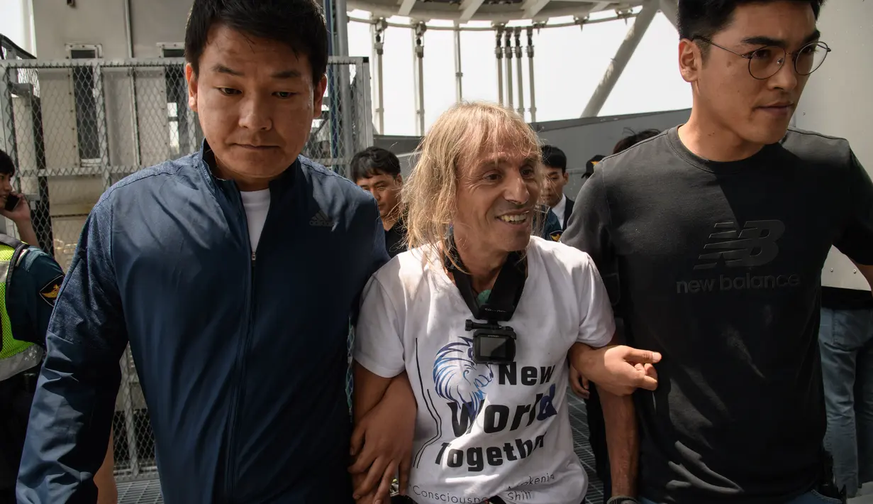 Urban climber atau pemanjat gedung, Alain Robert diamankan petugas setempat saat memanjat Menara Lotte World di Seoul, Korea Selatan (6/6). (AFP/Ed Jones)