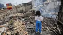 Seorang anak mencari sisa sisa barang paska kebakaran di permukiman kumuh di RW 02 Kampung Walang, Lodan Raya, Jakarta, Minggu (25/8). Kondisi Kampung Walang kini porak-poranda. (Liputan6.com/Faizal Fanani)