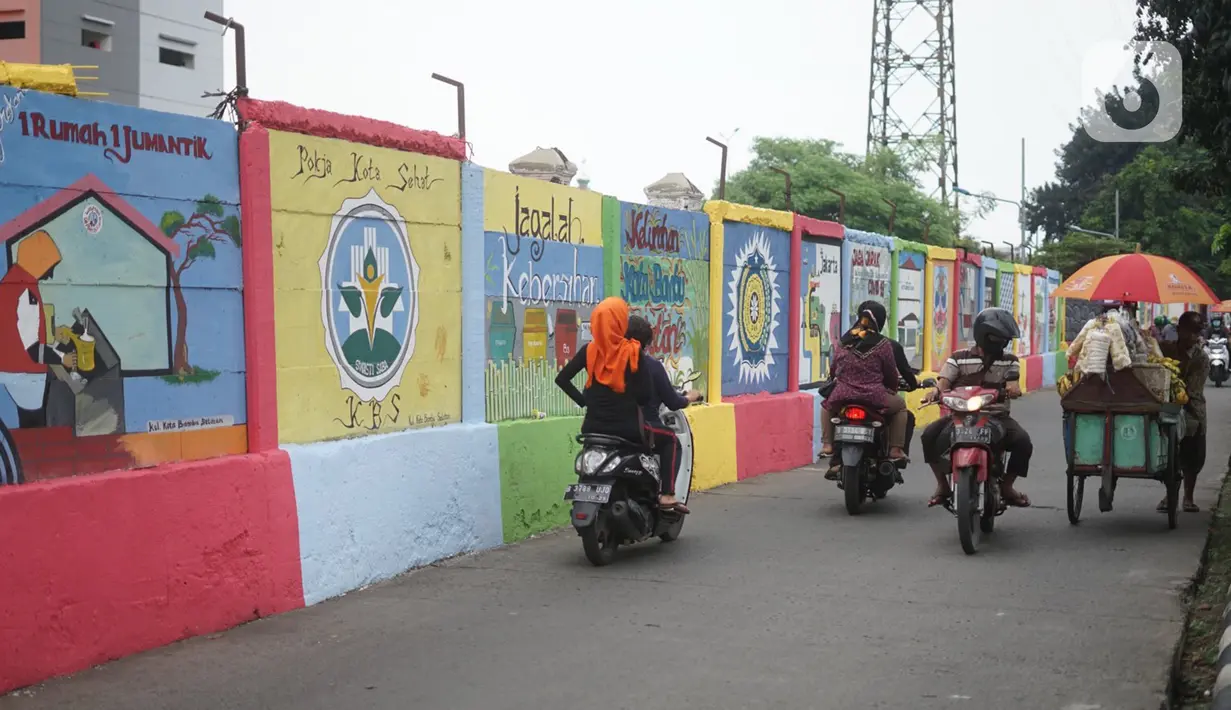 Pengguna jalan melintas di depan mural bertema Kota Jakarta di sekitar Rusunawa KS Tubun, Jakarta, Senin (23/11/2020). Mural tersebut dibuat guna memercantik lingkungan di sekitar rusun agar lebih berwarna dan tidak tampak kumuh. (Liputan6.com/Immanuel Antonius)