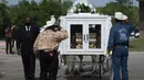 Dua koboi memberi hormat kepada jenazah George Floyd yang dibawa kereta kuda menuju pemakaman Houston Memorial Gardens di Houston, Texas, Amerika Serikat, Selasa (9/6/2020). Floyd akan dimakamkan di samping makam ibunya, Larcenia Floyd. (Andrew CABALLERO-REYNOLDS/AFP)