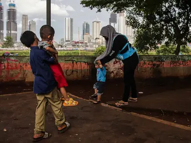 Sejumlah anak bermain di taman bermain yang terdapat di Bantaran Banjir Kanal Barat Kawasan Petamburan, Jakarta, Minggu (12/12/2021). Taman di bantaran kali kawasan padat penduduk itu menjadi sarana bermain bagi anak-anak di sekitarnya. (Liputan6.com/Faizal Fanani)