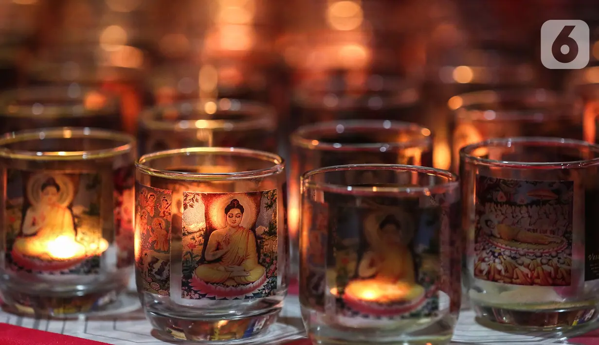 Deretan lilin dalam gelas terlihat saat umat Buddha melakukan sembahyang Puja Bakti Waisak di Vihara Avalokitesvara Pondok Cabe, Tangerang Selatan, Banten, Senin (16/5/2022). Ibadah perayaan Hari Raya Waisak 2566 BE berlangsung khidmat dengan mengusung tema "Dalam Cinta Kasih, Semua Bersaudara". (Liputan6.com/Johan Tallo)