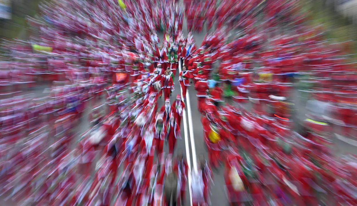 Orang-orang mengenakan kostum Sinterklas ambil bagian dalam Santa Claus Run di Madrid, Spanyol, Minggu (9/12). Ribuan orang berjalan dan berlari dalam perlombaan Santa tahunan melintasi jalan-jalan ibu kota Spanyol. (Gabriel BOUYS / AFP)