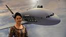 Pramugari berpose di depan poster SIA Airbus A380 saat peluncuran kabin terbaru di Singapura, (2/11). Kabin first class, business class, dan economy class ini tersedia di lima pesawat Airbus A-380 Singapore Airlines. (AFP Photo/Roslan Rahman)