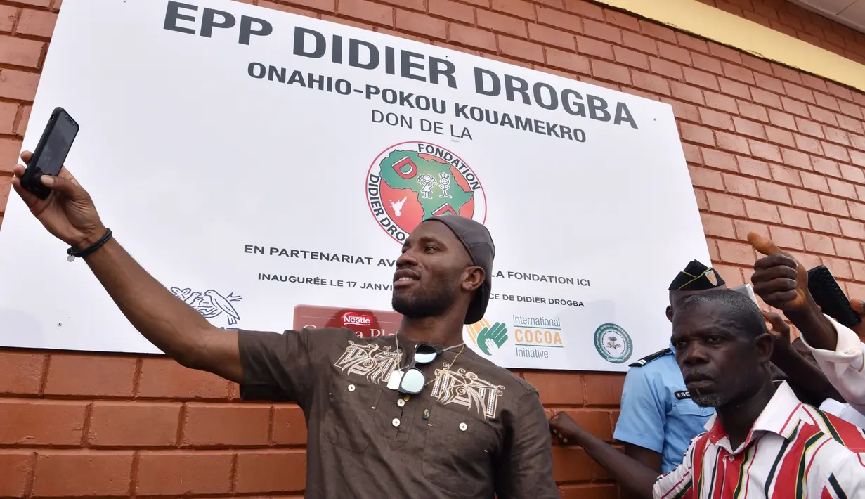 Bintang sepak bola asal Pantai Gading, Didier Drogba melakukan foto selfie saat membuka sekolah di Onahio, Pokou-Kouamekro, Pantai Gading, (20/1/2018).  Drogba menjadi salah satu sponsor utama untuk sekolah tersebut. (AFP/Sia Kambou)
