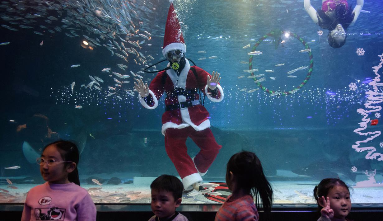 Penyelam berpakaian Sinterklas menyapa anak-anak saat tampil dalam pertunjukan bawah laut bertema Natal di Akuarium COEX, Seoul, Korea Selatan, Jumat (7/12). (Ed JONES/AFP)