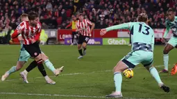 Gelandang Brentford, Mathias Jensen (kiri) melepaskan tendangan yang berbuah gol ke gawang Fulham pada laga Liga Inggris 2022/2023 di Gtech Community Stadium, London (6/3/2023). Mathias Jensen didatangkan dari Celta Vigo pada awal musim 2019/2020 dengan nilai transfer 3,8 juta euro saat Brentford masih berkompetisi di Championship. Masuk dalam skuad inti musim ini, ia selalu bermain dalam seluruh 24 laga Brentford di Liga Inggris dengan torehan 4 gol dan 4 assist. (AFP/Adrian Dennis)