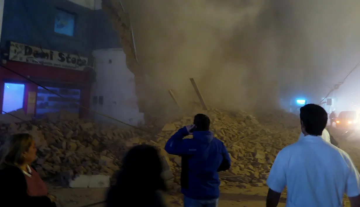 Sejumlah orang menyaksikan puing gedung bioskop tua yang tengah direnovasi sesaat setelah runtuh di Tucuman, Argentina, Rabu (23/5).Sedikitnya satu orang tewas akibat kejadian tersebut. (AFP PHOTO/Walter Monteros)
