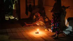 Hingga Selasa 16 Desember 2025 malam, warga yang mengungsi akibat banjir bandang pada akhir November 2025 bertahan hidup dalam kegelapan malam tanpa penerangan lampu listrik. Tampak dalam foto, Nurlimah (C), 65 tahun, yang tidak dapat berjalan sejak mengalami cedera dalam kecelakaan tabrak lari setahun lalu, duduk sambil berlindung di rumah tetangga yang sebagian runtuh di sebelah rumahnya, yang hanyut tersapu banjir bandang di Aceh Tamiang, pada Selasa 16 Desember 2025. (Yasuyoshi Chiba/AFP)
