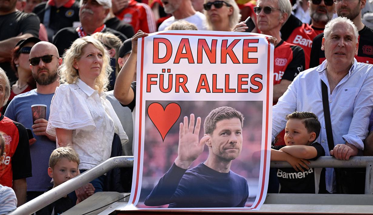 Pendukung Bayer Leverkusen memegang poster pelatih, Xabi Alonso dalam acara perpisahan setelah laga lanjutan Liga Jerman 2024/2025 melawan Borussia Dortmund di BayArena, Leverkusen, Jerman, Minggu (11/05/2025) waktu setempat. (AFP/Ina Fassbender)