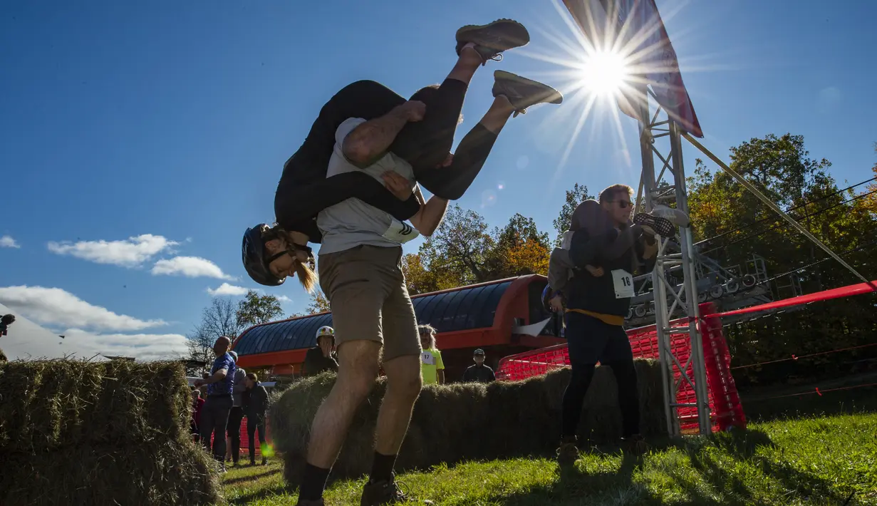 Tim bersiap untuk berlari menjelang North American Wife Carrying Championship di Sunday River Resort di Newry, Maine, pada 8 Oktober 2022. Untuk gaya menggendong, festival ini memiliki 3 jenis gaya, yakni piggyback (gendong di punggung), fireman carry (gendong di bahu) dan estonian style (gendong di punggung namun posisi wanita terbalik dengan kepala di bawah). (Joseph Prezioso / AFP)