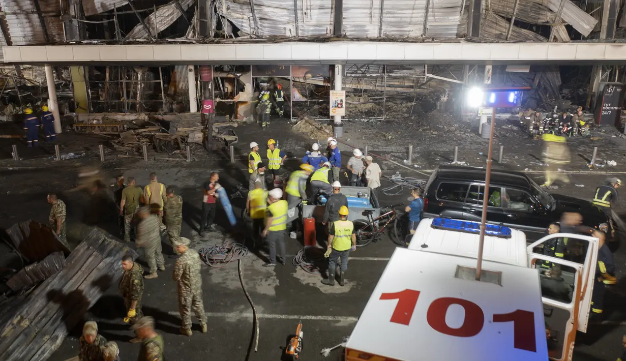 Sejumlah relawan bekerja untuk mengambil puing-puing di pusat perbelanjaan yang terbakar setelah serangan roket di Kremenchuk, Ukraina, Selasa (28/6/2022) pagi. (AP Photo/Efrem Lukatsky)