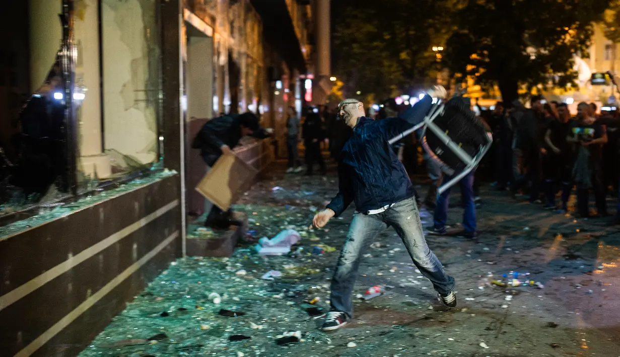 Pengunjuk rasa melempar kursi ke jendela kantor Presiden Gjorge Ivanov di ibu kota Makedonia, Skopje, Rabu (13/4). Ribuan demonstran melakukan unjuk rasa memprotes keputusan Presiden memberikan pengampunan bagi 56 politikus. (Robert ATANASOVSKI/AFP)