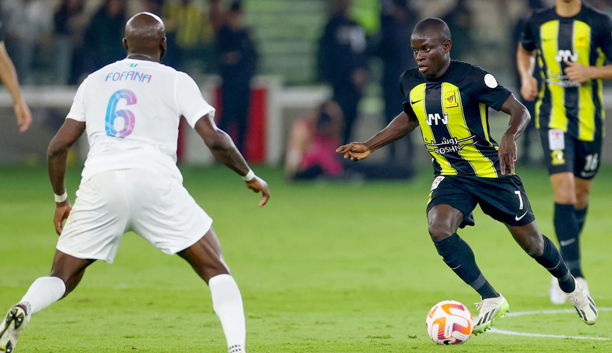 Pemain Al Ittihad, N'Golo Kante, berusaha melewati pemain Al Nassr, Seko Fofana, dalam laga tunda pekan ke-17 Liga Arab Saudi di King Abdullah Sport City Stadium, Jeddah, Rabu (27/12/2023). (Photo by AFP)
