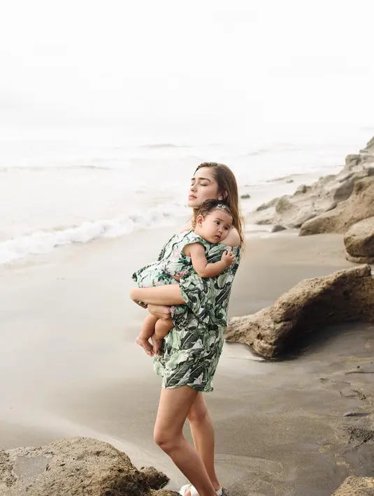 Liburan ke pantai, Yasmine kompak bersama si buah hati memakai baju kembar. Gadis mungil ini tampak nyaman berada di gendongan sang ibu. (Instagram/yaswildblood)