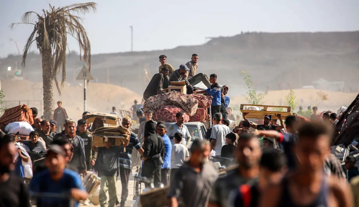 Orang-orang berjalan membawa paket bantuan kemanusiaan yang mereka terima dari pusat distribusi yang dikelola oleh Yayasan Kemanusiaan Gaza (GHF) yang didukung Amerika Serikat (AS) dan Israel, di koridor Netzarim, Nuseirat, Jalur Gaza tengah, pada 30 September 2025. (Eyad BABA/AFP)