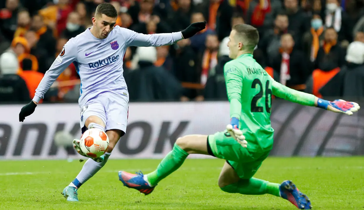 Penyerang Barcelona Ferran Torres (kiri) melakukan tembakan di depan kiper Galatasaray Inaki Pena pada leg kedua 16 besar Liga Europa di NEF Stadyumu, Jumat (18/3/2022) dini hari WIB. Hasil Galatasaray vs Barcelona berakhir dengan skor 1-2. (KEMAL ASLAN / AFP)