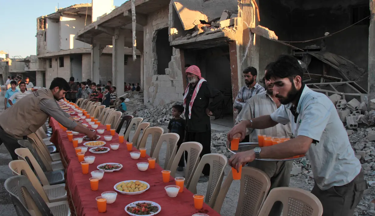 Warga Suriah menyiapkan hidangan buka bersama di tengah reruntuhan bangunan di Kota Douma di pinggiran ibukota Damaskus, Suriah, (18/6). (AFP Photo/Hamza Al-Ajweh)