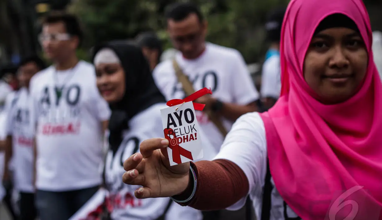 Seorang aktivis tampak menunjukkan stiker bertuliskan 'Ayo Peluk ODHA' di Bundaran HI, Jakarta, Minggu (28/12/2014). (Liputan6.com/Faizal Fanani)