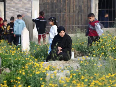 Warga Palestina mengunjungi makam kerabatnya usai melaksanakan salat Idul Fitri 1446 Hijriah di kamp Nuseirat, Jalur Gaza tengah pada 30 Maret 2025. (Eyad BABA/AFP)