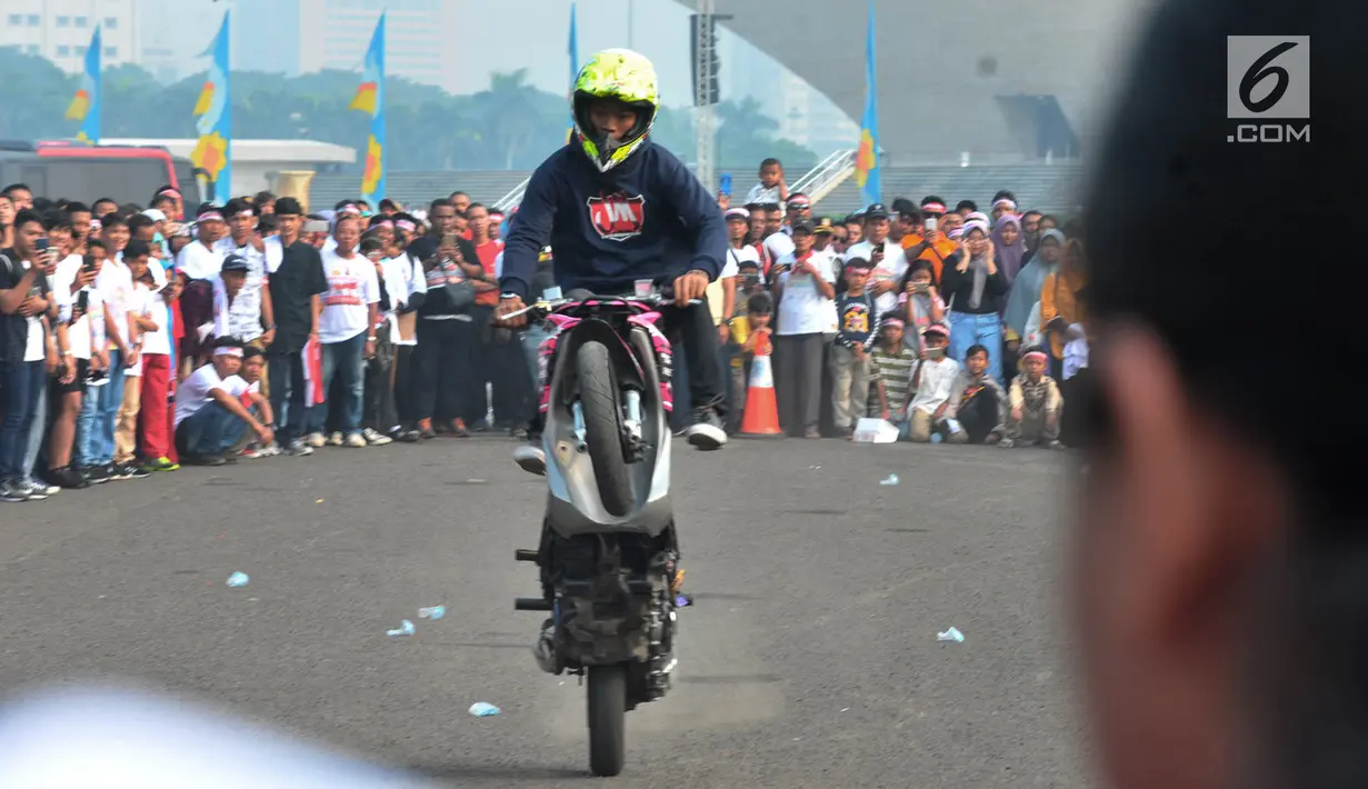 Freestyler melakukan atraksi freestyle sepeda motor saat memeriahkan Festival Damai Millenial Road Safety di Monas, Jakarta, Minggu (23/6/2019). Festival ini juga dimeriahkan oleh berbagai atraksi dan pertunjukan musik artis Tanah Air. (merdeka.com/Iqbal Nugroho)