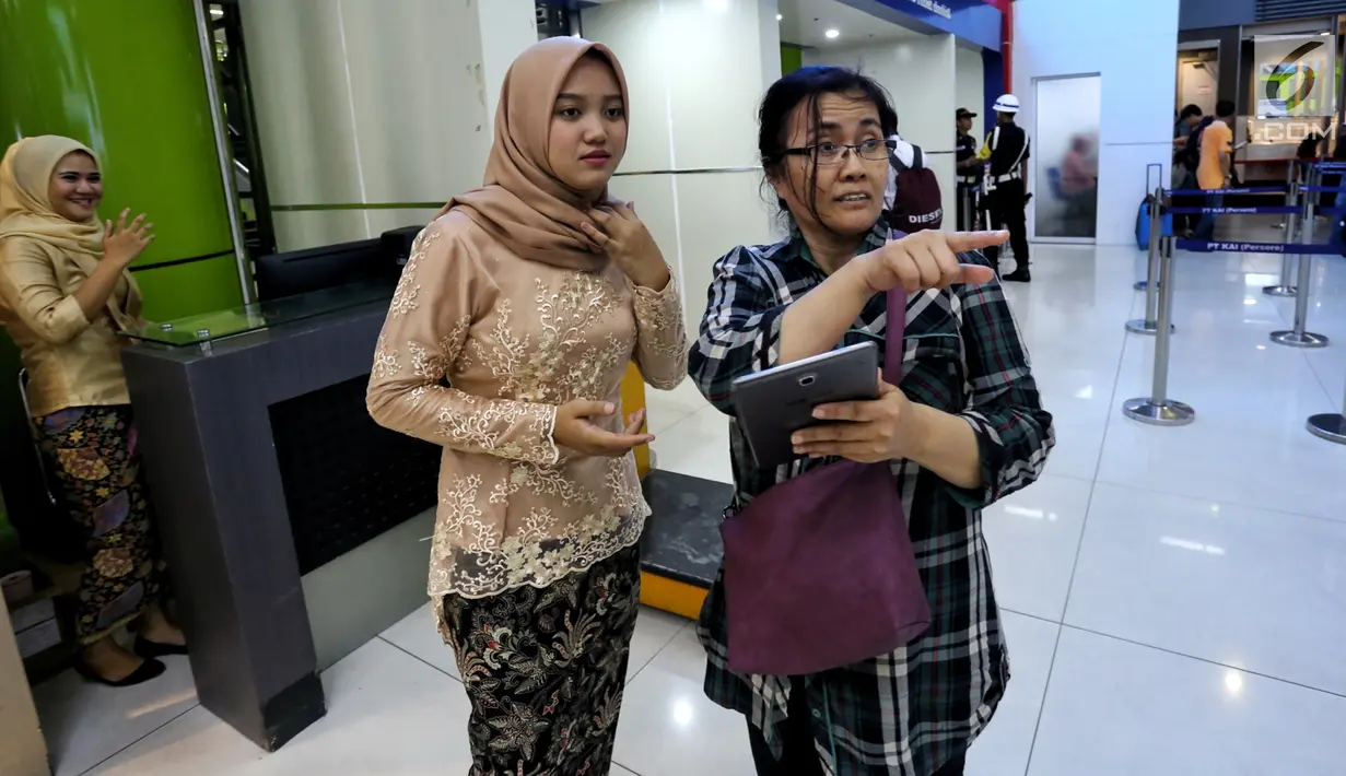 Petugas frontliner berpakaian tradisional membantu calon penumpang di Stasiun Gambir, Jakarta, Minggu (21/4). PT KAI Daop 1 Jakarta mewajibkan petugas frontliner wanita dan pria mengenakan kebaya dan batik untuk menyambut Hari Kartini. (Liputan6.com/Johan Tallo)