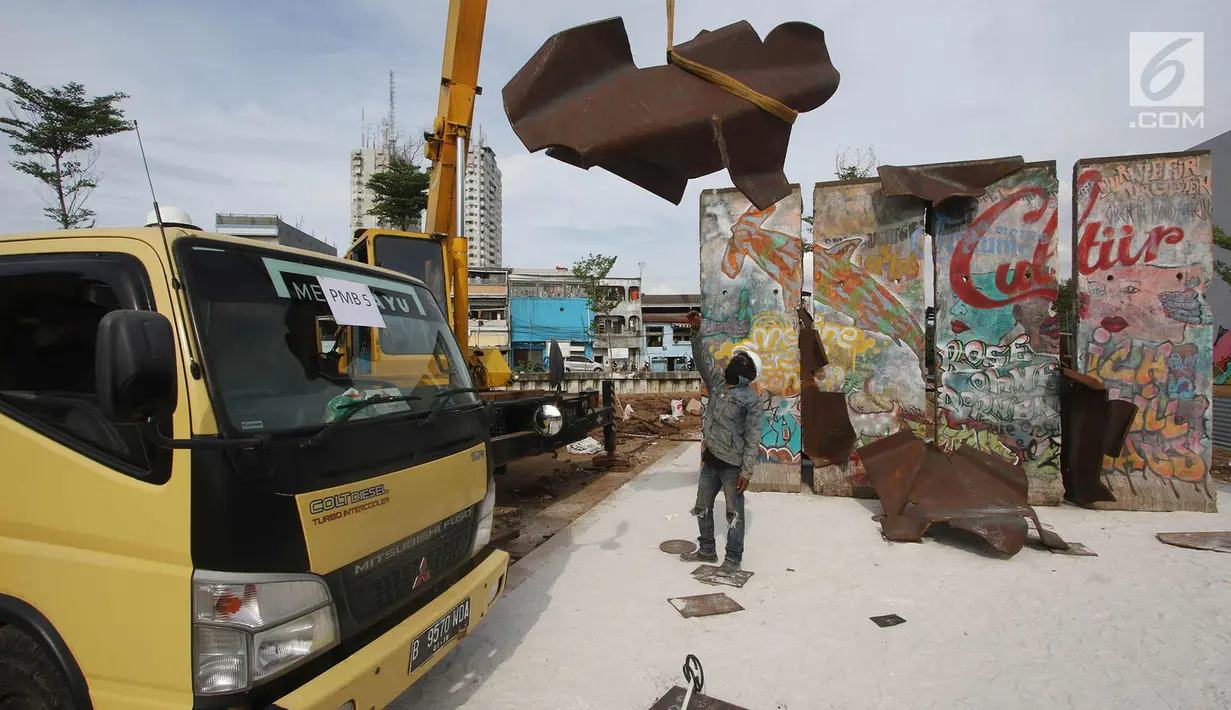 Pekerja memasang bongkahan Tembok Berlin dan Patung Menembus Batas di RPTRA Kalijodo, Jakarta, Selasa (26/9). Hal ini bertujuan agar masyarakat bisa melihat langsung tembok bersejarah itu. (Liputan6.com/Immanuel Antonius)